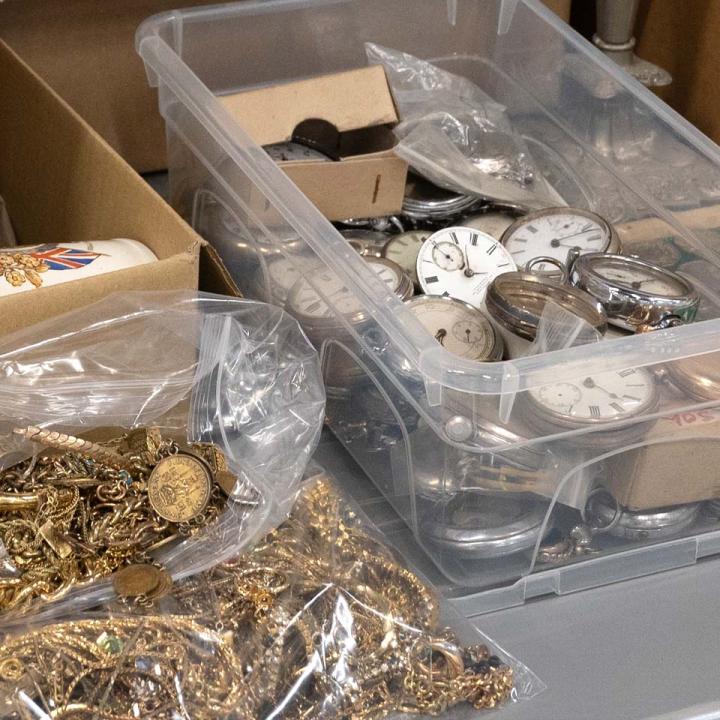 Bags of costume jewellery and a box of pocket watch movements, illustrating the types of items sold