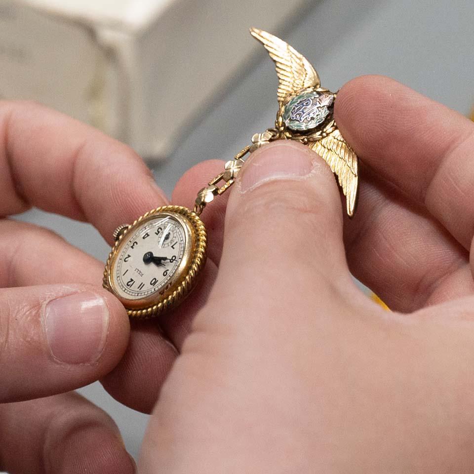 Close up image of hands holding an antique pin watch